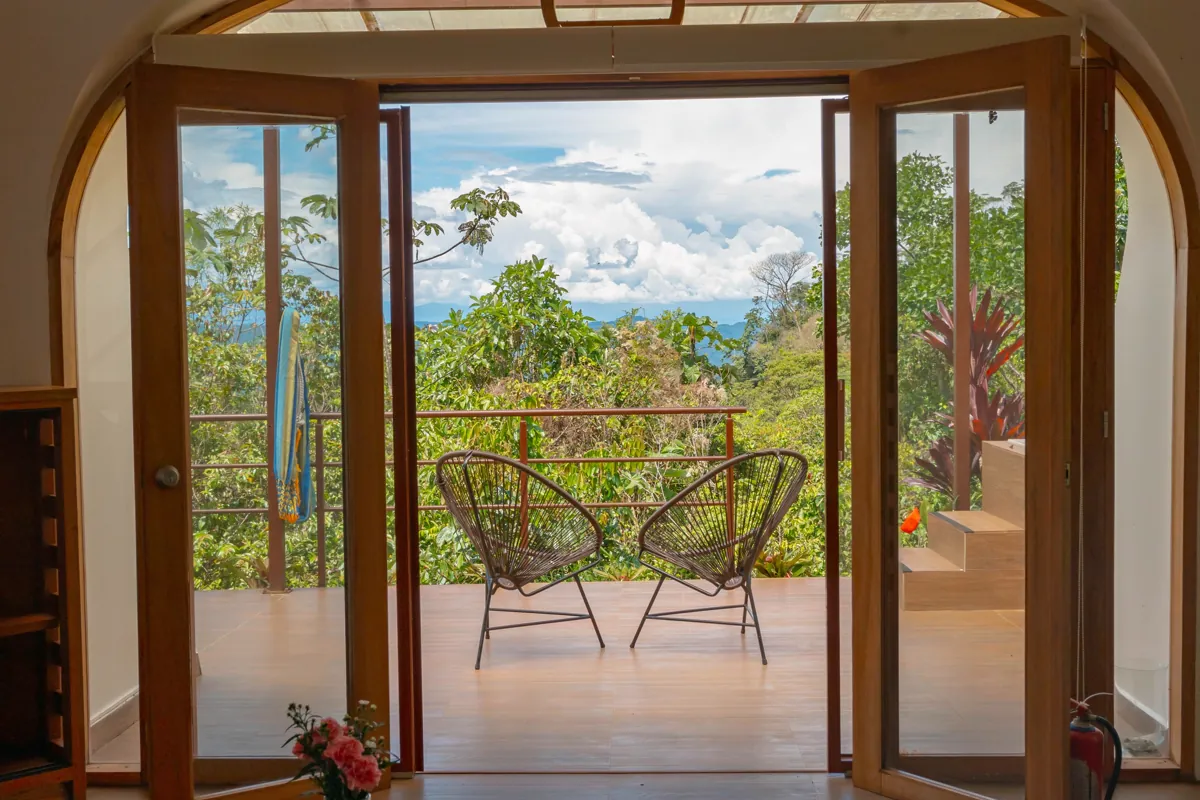 Room doors opening onto a wooden terrace with two chairs above the valley